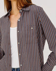 Woman wearing a striped shirt over a white top with a neutral background