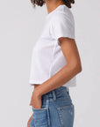Person wearing a white t-shirt and blue jeans on a plain background