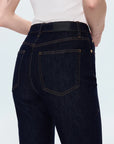 Dark blue jeans worn by a person on a light gray background