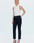 Woman wearing a white sleeveless top and black jeans on a light gray background