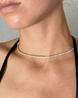 Close-up of a person wearing a delicate gold necklace with a neutral background