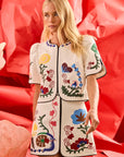 Woman wearing a white outfit with colorful floral patterns against a red background