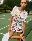 Woman in a colorful embroidered outfit on a tennis court