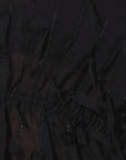 Close-up of a black sheer mesh fabric with vertical ruching and small reflective embellishments.