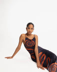 Woman sitting, wearing a dress with spiral pattern on a white background