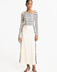 Woman wearing a Navy and white striped long-sleeve top and cream skirt on a white background