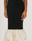 Black dress with a cream-colored ruffled bottom on a white background detail view