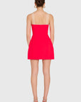 model wearing a red dress with ivory straps standing on a white background, back view
