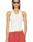 A woman modeling a fitted white ribbed tank top paired with red drawstring pants against a plain white background.