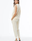 Woman wearing a cream-colored outfit on a white background, back