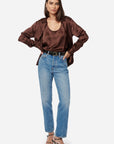 Woman wearing a brown satin blouse and blue jeans on a white background
