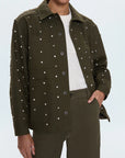 Person wearing a green military-style jacket with silver studs on a white background