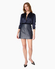 model wearing a leather navy skirt and long sleeve navy top on a white background