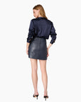 model wearing a leather navy skirt and long sleeve navy top on a white background, back