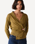Woman wearing a green cardigan over a blue top on a white background