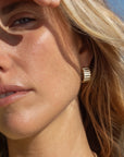 Close-up of a woman wearing gold earrings with a blurred background