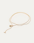 Gold necklace with a small pendant on a light beige background