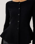 close up of a model wearing a black button down peplum caridgan with jeans on a grey background