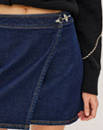 Close-up of a person wearing a blue denim skirt with a black sweater.