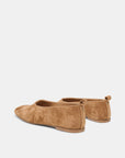 A pair of tan suede flat shoes shown from a rear three-quarter angle on a light gray background.