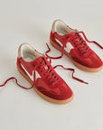 Red sneakers with brown soles on a light gray background