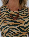 Person wearing a tiger-striped dress with a necklace featuring brown beads.