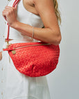 Person holding a red woven handbag against a plain background