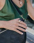 Detail of a person holding a black grande fanny with a gold ring on a blurred background