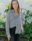 Woman wearing Aris Shirt in Solene Stripe black pants standing outdoors with greenery in the background front view