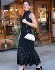Woman in a black dress with a white handbag side
