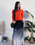 Woman wearing an orange sweater and black and gray skirt