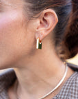 Close-up of a person wearing a gold hoop earring.