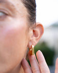 Close-up of a person wearing a gold earring with a blurred background