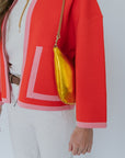 Person wearing a red jacket with a gold handbag on a white background