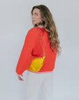 Woman wearing a red jacket with a yellow handbag on a plain background