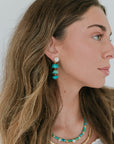 Woman wearing turquoise earrings, necklace and Paloma Chain - L with a white background