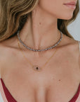 Close-up of a woman wearing two necklaces with a plain background