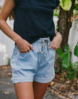 Person wearing a navy blue top and light blue shorts in an outdoor setting.