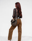Woman wearing a leopard print outfit with a black sheer top and brown patterned pants, holding a matching bag. back