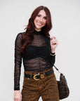 Woman wearing The Love Language Long Sleeve Top and leopard print pants with a white background