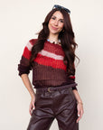 Woman wearing a striped sweater and leather pants against a plain background, close up