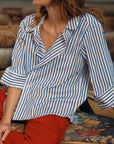 Person wearing a blue and white striped shirt with red pants sitting on a patterned rug.