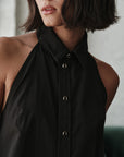 Person wearing a black halter neck top with a blurred background