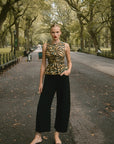 Woman in a park wearing a tiger-striped top and black pants.