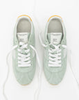 Pair of light green sneakers with white laces on a white background