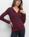Woman wearing a burgundy sweater with blue stripes against a white background