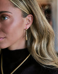model wearing teardrop earrings and a black top with a snake chain necklace