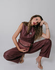 Woman in a maroon outfit with a checkered handbag posing against a plain background