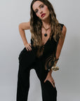 Woman wearing a black outfit leaning forward against a plain background