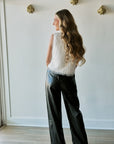 model wearing a white tassel top and black bottoms, back view